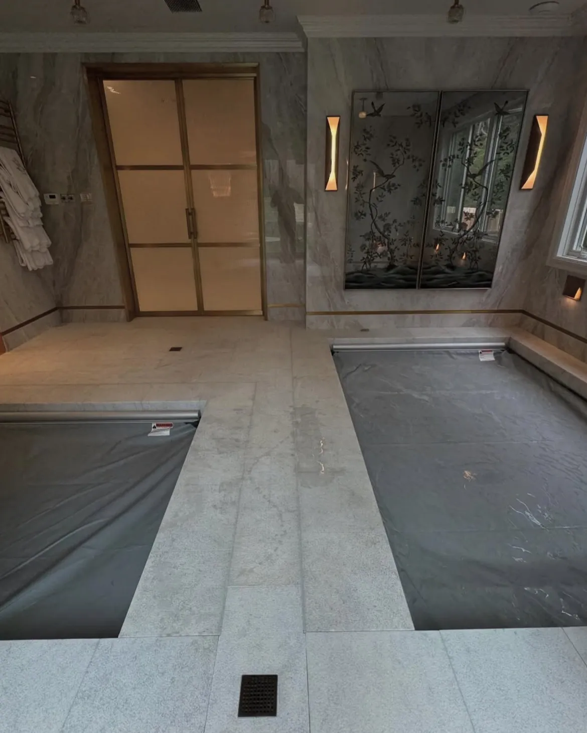 Indoor pool and spa with light stone tile and grey automatic covers closed over both bodies of water.