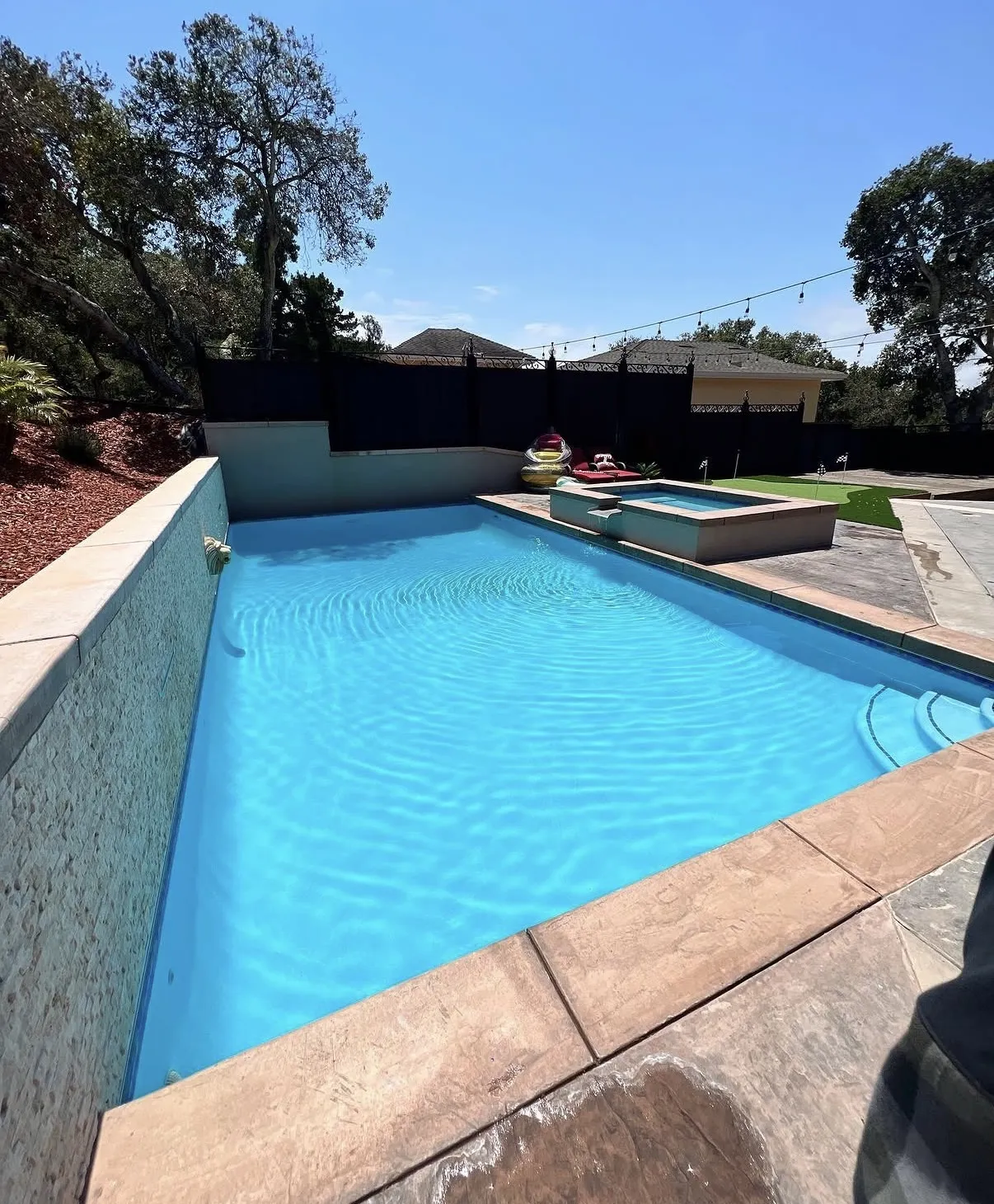 Finished rectangular pool with a raised spa, spillover, and a raised side wall featuring a lion head water spout.